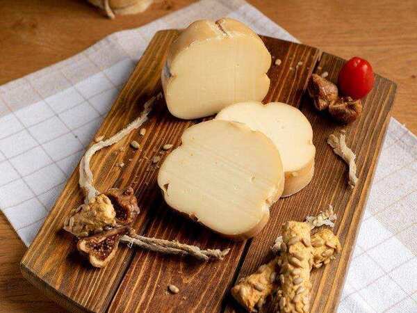 Greek Cheese Guide: 12 Traditional Varieties 10 Traditional smoked Greek Metsovone cheese sliced on a wooden board
